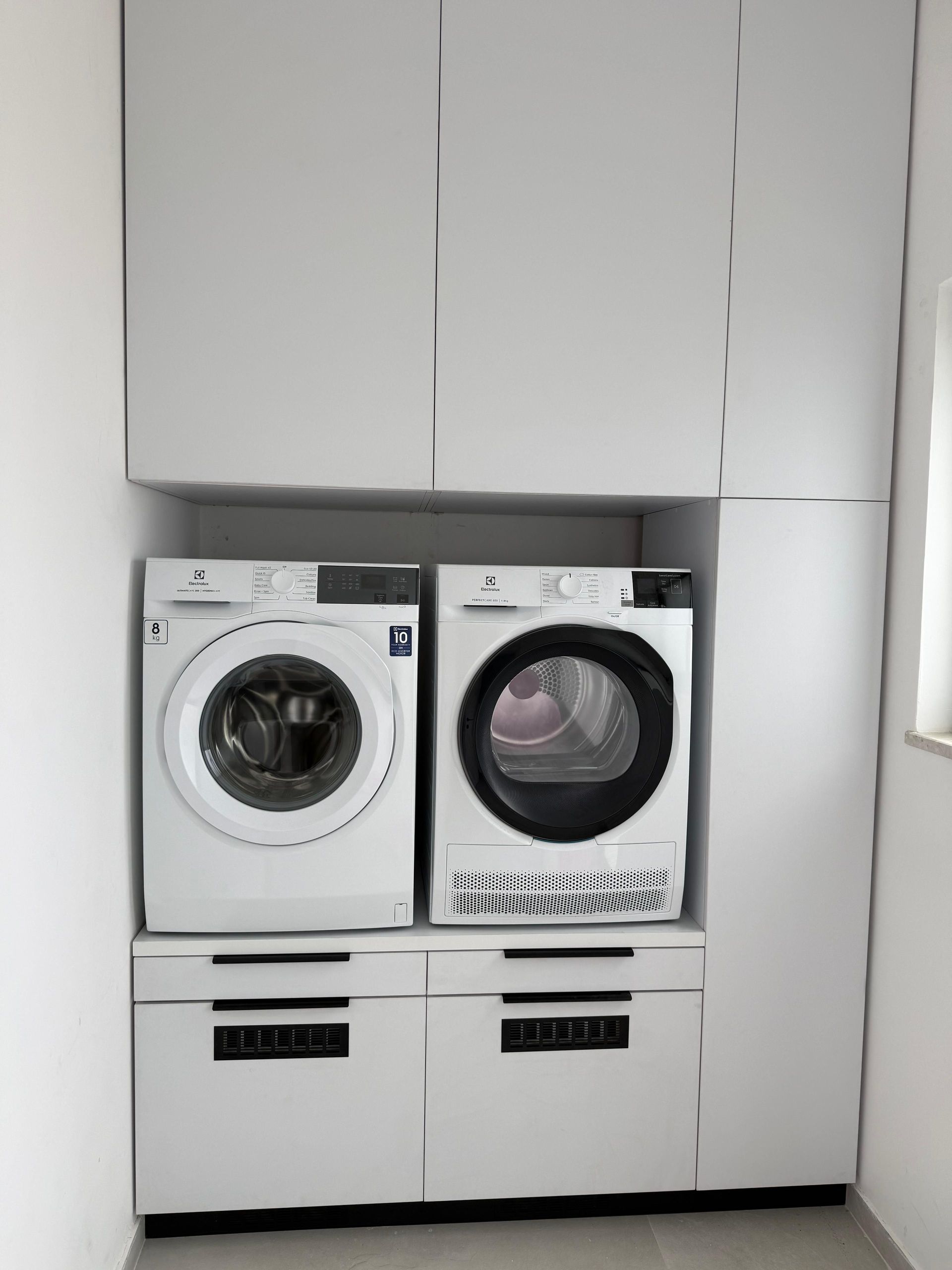 Contemporary indoor laundry room featuring a washer and dryer in sleek storage cabinetry.