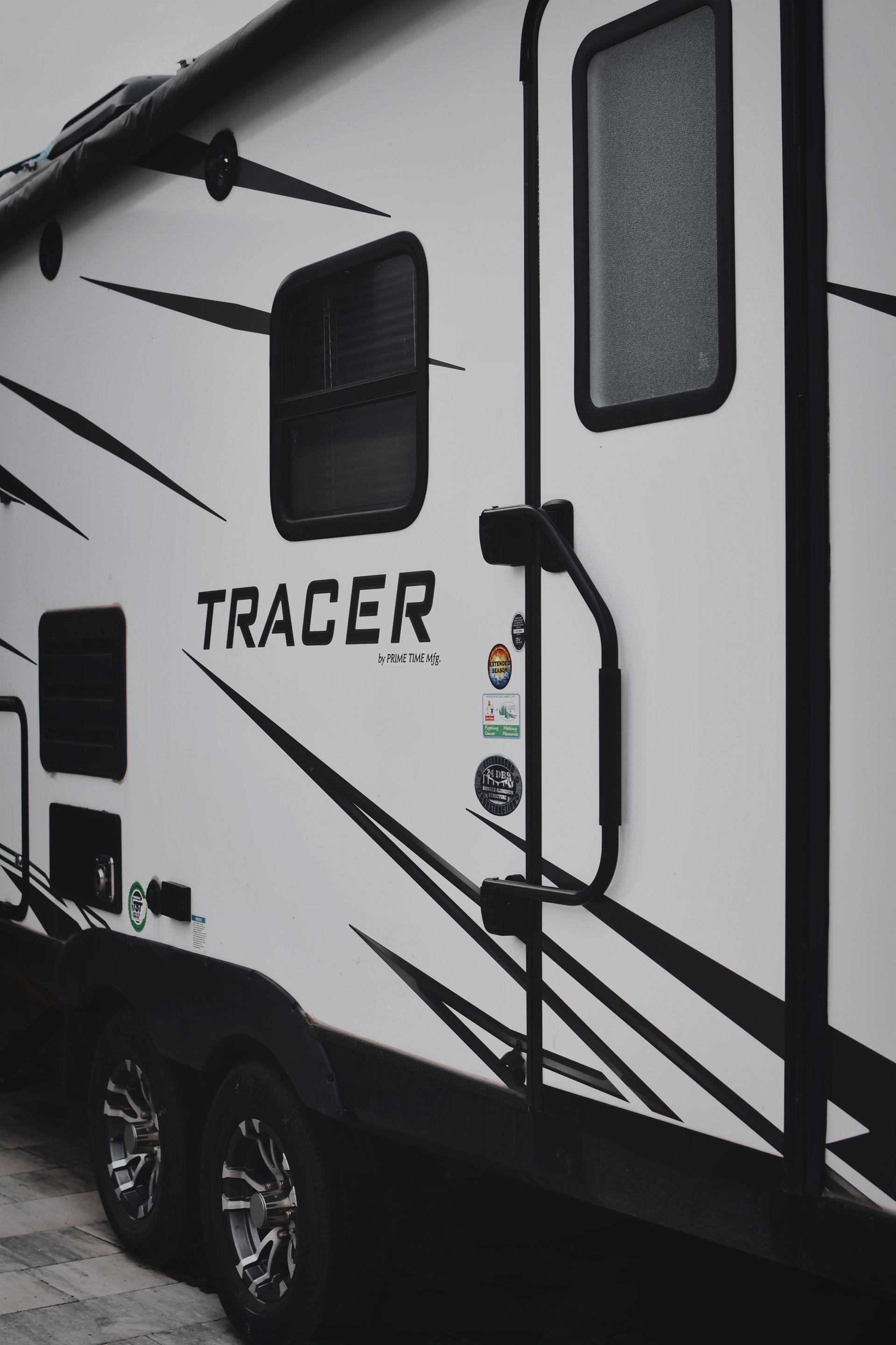Detailed close-up of the Tracer camper showing door, decals, and wheels for RV enthusiasts.